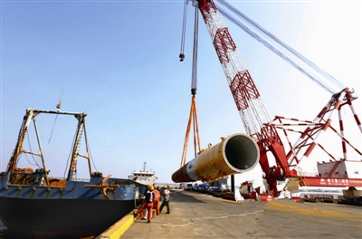 8月11日，投資12億元由江蘇長鑫龍海上裝備公司自主研發(fā)并生產(chǎn)的首套36根鋼管樁，通過江蘇大豐港直運如東海上風電工地。圖為吊裝鋼管樁現(xiàn)場