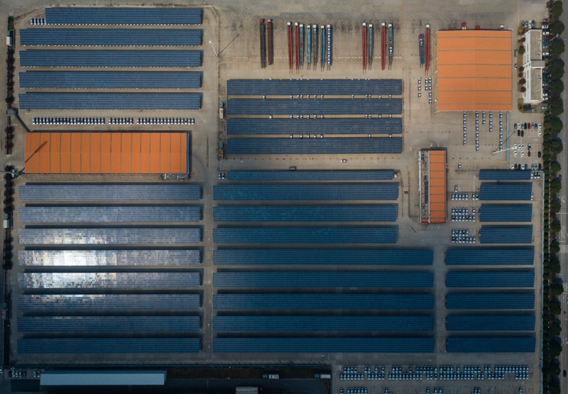 
	中國儲能網(wǎng)訊：位于江蘇南京江寧區(qū)上海大眾汽車南京分公司廠內(nèi)的光伏車棚，總面積大約20萬平方米。光伏車棚內(nèi)，在每一排車棚靠頂部的地方都有一個電視機大小的四方盒子，底部還連接著10多根電纜，車棚的頂部則是一塊塊反光板