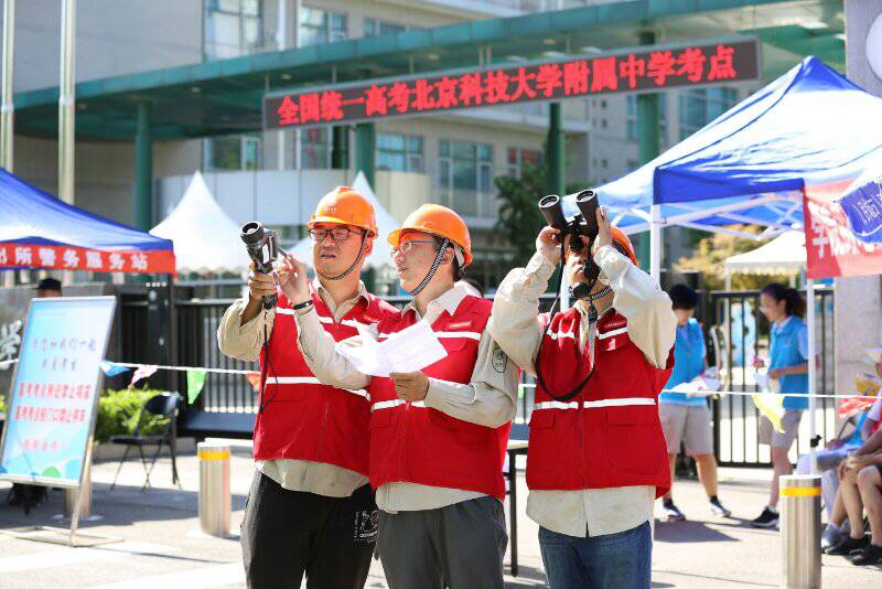 海淀供電公司的高考保電人員在北京科技大學(xué)附屬中學(xué)的保電現(xiàn)場，用高倍望遠(yuǎn)鏡、測溫儀等設(shè)備對10千伏高考供電重點線路進(jìn)行特巡、測溫、測負(fù)荷工作。（攝影：王洋）　　 6月7日一大早，北京科技大學(xué)附屬中學(xué)兩旁的街道上還只有稀稀落落的行人，考生也都還未抵達(dá)考場，國網(wǎng)北京海淀供電公司員工李揚、朱勁東卻早已開始了線路巡視工作