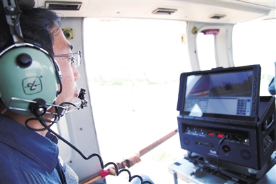 
　　直升機上技術(shù)人員通過各類終端屏幕和傳感數(shù)據(jù)，對線路進行驗收。鄭建榮 攝

　　直升機搭載好各類高科技器材，準備起飛