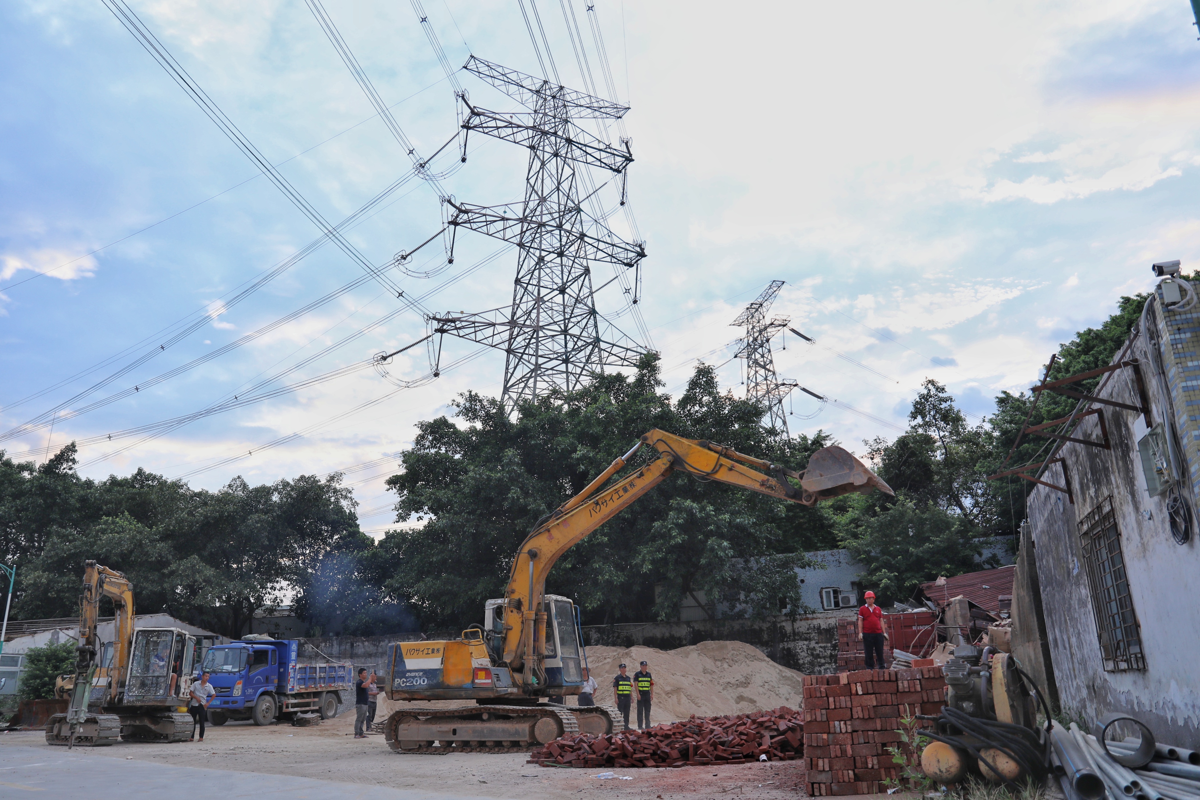 　　臺(tái)風(fēng)“山竹”來(lái)襲前夕，位于龍崗六約扣車場(chǎng)的幾間鐵皮房前，80名工作人員3臺(tái)大型勾機(jī)緊張忙碌著。這是南方電網(wǎng)深圳供電局正在當(dāng)?shù)亟值擂k支持下，對(duì)可能影響500千伏深圳變電站涉港涉核線路安全穩(wěn)定運(yùn)行的隱患點(diǎn)進(jìn)行拆除